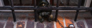 WROCLAW, POLAND - APRIL 18, 2022: Gnome statue and grid on windowsill on urban street, banner  clipart