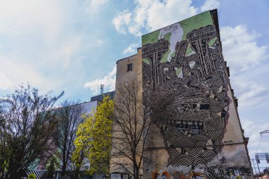 WROCLAW, POLAND - 18 Nisan 2022: Kentsel caddedeki eski binanın önünde duvar resmi 