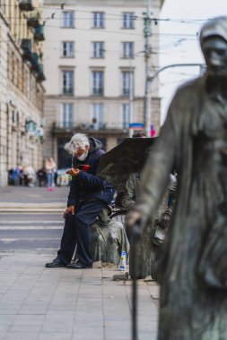 WROCLAW, POLAND - APRIL 18, 2022: Man reading book near Anonymous Pedestrians memorial on urban street  clipart