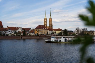WROCLAW, POLAND - 18 Nisan 2022: Arka planda binalar olan nehir kıyısında tekne 
