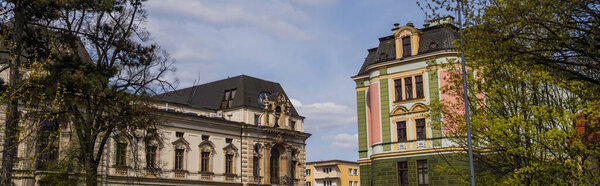 Trees near old buildings on urban street, banner 