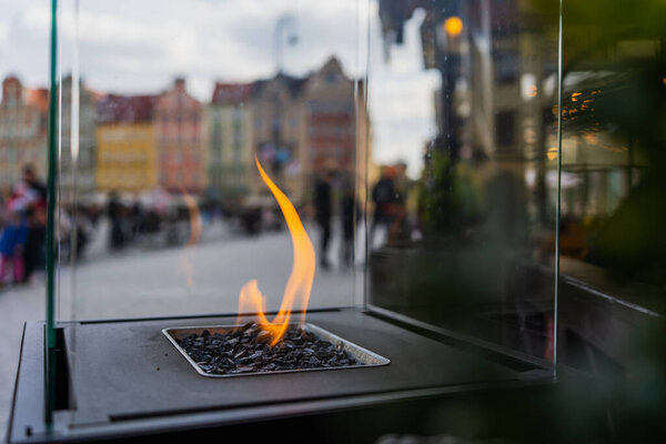 Close up view of fire in glass box on blurred street in Wroclaw