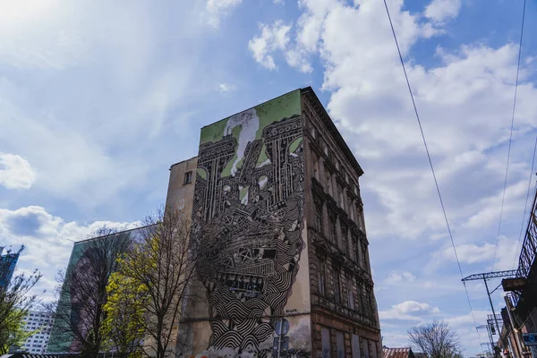 WROCLAW, POLAND - 18 Nisan 2022: Kentsel cadde üzerindeki duvar resmi binasının alçak açılı görünümü 