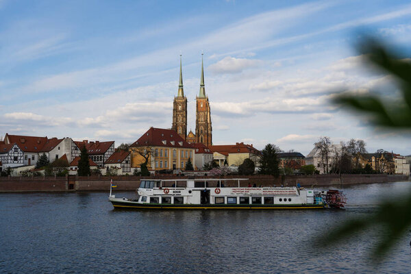 WROCLAW, POLAND - APRIL 18, 2022: Boat on river water with buildings on embankment at background 