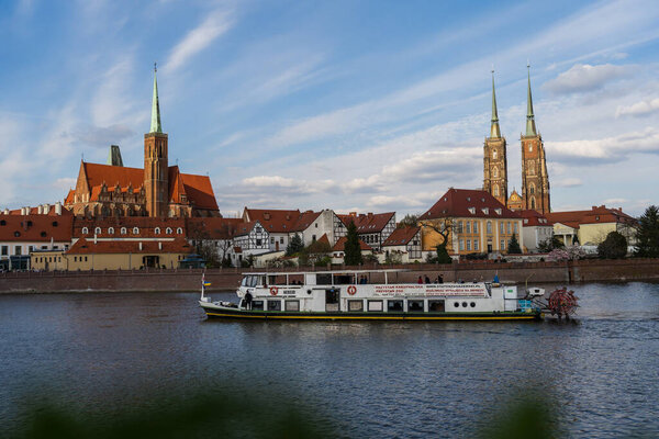 WROCLAW, POLAND - APRIL 18, 2022: Boat on river with St John Baptist church at background 