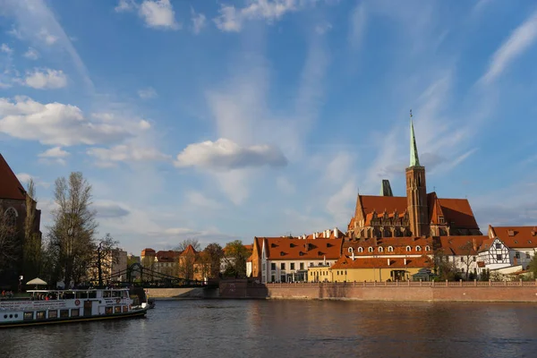WROCLAW, POLAND - 18 апреля 2022 года: Река и церковь на Остроу Тумски днем — стоковое фото