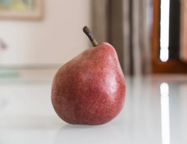 Beyaz yansıtıcı yüzeyde izole edilmiş kırmızı bir armut.