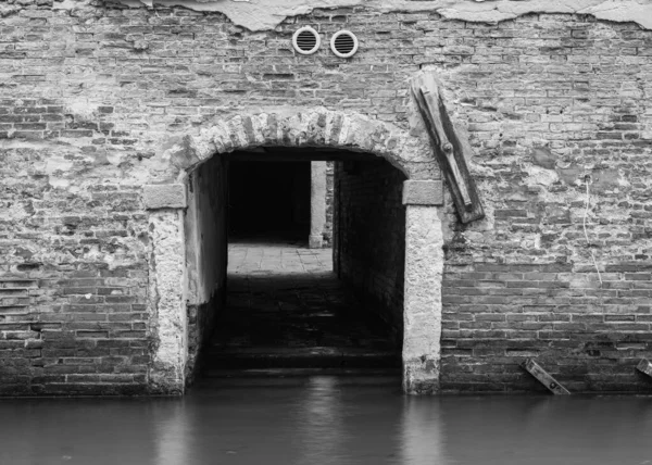 black and white photo with depth of an alley by a canal in Venice, Italy