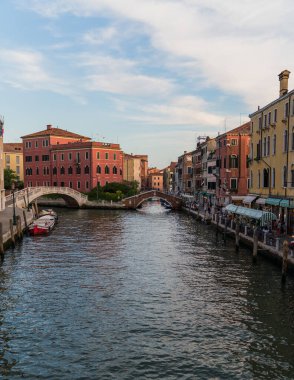 Beautiful view of a canal in Venice, Italy around sunset and traditional architecture on the background 