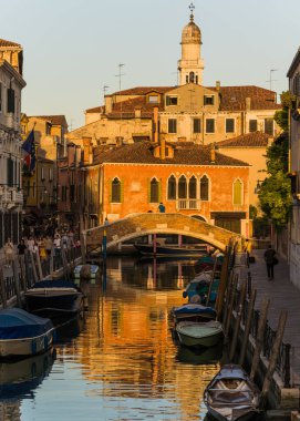 Beautiful view of a canal in Venice, Italy around sunset and traditional architecture on the background 