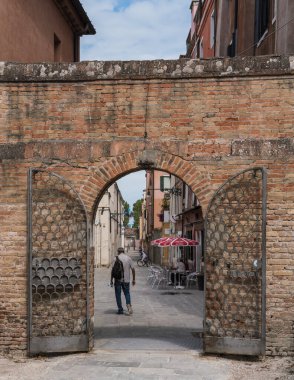 old arched entrance to a park in Venice, Italy and man walking by