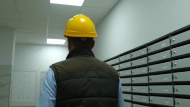 Sarı miğferli bir adam, bina içinde içeri doğru yürüyordu. Yetişkin erkek müteahhit binanın içinde yürüyor. Kapatın. İnşaat konsepti, iş, meslek.