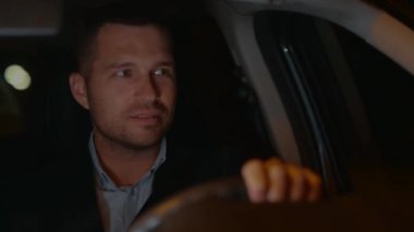 Arabanın içinde takım elbiseli yakışıklı, neşeli genç adama yaklaş. Başarılı bir iş adamı geceleri yola bakarak otomobilini sürüyor. İş gezisi. Olumlu duygular. Seyahat kavramı