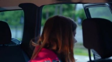 Close up of Caucasian young pretty teenage girl gets in the car putting medical mask on face and fastening safety belt. Taxi service, cab concept. Car trip. Pandemic covid-19, healthcare protection