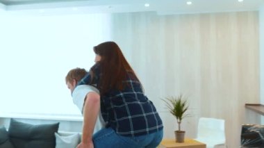 Close up of cheerful Caucasian man and woman having fun playing in new house on moving day. Piggyback ride. Happy young family couple in home with many boxes moving in together. New home concept