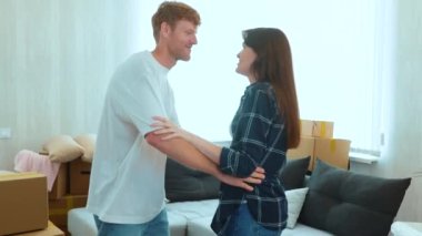 Close up of young Caucasian family husband and wife dancing in room in new apartment on moving day. Cheerful joyful married couple dance in new house with boxes. Relocation. Boyfriend and girlfriend