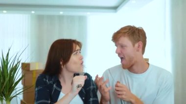 Close up of happy positive couple handsome man and pretty woman singing and dancing using kitchen utensil as microphone. New apartment. Relocation. Married people having fun in new house. Slow motion
