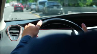 Close up shot of male hands on steering wheel inside the car driving vehicle looking at road in city. Over shoulder view of man driver drives an auto. Traffic on background. Traveling. Trip concept