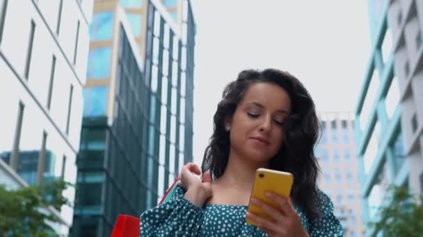 Cheerful Young Woman Walking Street Paper Bags Shopping Texting Smartphone — Stockvideo