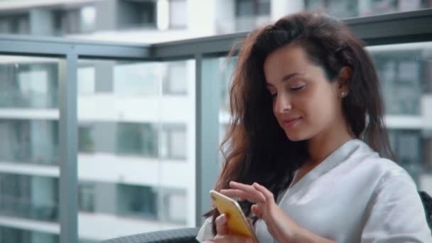 Όμορφη Νεαρή Γυναίκα Κάθεται Ένα Μπαλκόνι Και Γραπτών Μηνυμάτων Smartphone — Αρχείο Βίντεο
