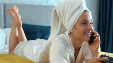 Duş aldıktan sonra Kafkas 'lı mutlu genç bayanı kapat. Gülümse ve akıllı telefondan konuş. Evde rahat bir şekilde televizyon izle. Güzel bir bayanın cep telefonuyla konuşması. İletişim konsepti