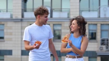 Beyaz, genç, mutlu bir çift, dışarıda duruyor ve çatıdaki bir partide pizza yiyorlar. Neşeli gülümseyen insanlar sohbet ediyorlar, fast food 'un tadına bakıyorlar. Portre çekimi