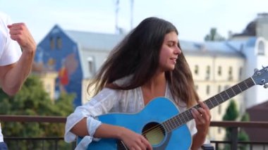 Neşeli gençler çatıdaki bir partide içki eşliğinde müzik dinleyerek dans ediyorlar. Mutlu Kafkasyalı güzel insanlar eğleniyor. Yaz zamanı. Güzel kadın dışarıda gitar çalıyor. Ağır çekim. Kapat.
