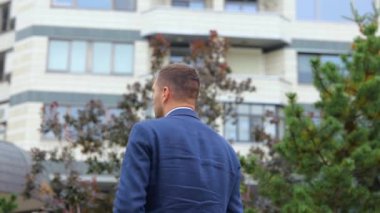 Dikiz aynası. Kamera, takım elbiseli, mutlu ve kendine güvenen genç bir adama yaklaşıyor. Dışarıda kameraya dönüyor ve gülümsüyor. Sokakta poz veren Kafkasyalı bir işadamı. İş konsepti, şehir, kapat