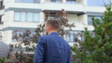 Dikiz aynası. Kamera, takım elbiseli, mutlu ve kendine güvenen genç bir adama yaklaşıyor. Dışarıda kameraya dönüyor ve gülümsüyor. Sokakta poz veren Kafkasyalı bir işadamı. İş konsepti, şehir, kapat