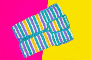 Pembe ve sarı arkaplanda izole edilmiş renkli örgü süveter, el örgüsü kumaş, kolsuz ceketin üst görüntüsü, sarı mor mavi süveter, kopyalama alanı