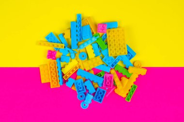 İstanbul, Türkiye - 10 Mayıs 2022: renkli lego blokları oyuncaklar, renkli arka plan, bir sürü lego bloğu, dökülen çocuk oyuncakları, yapı taşları, sarı ve pembe zemin, üst manzara