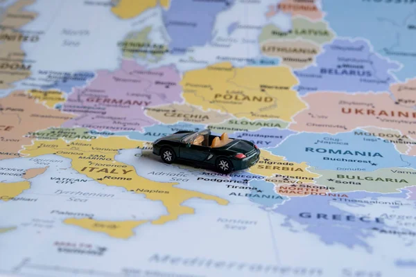 Toy car travels on Europe map, sitting view, vacation and destination concept, miniature green sport car going to Italy , worldwide tour, Europe map idea