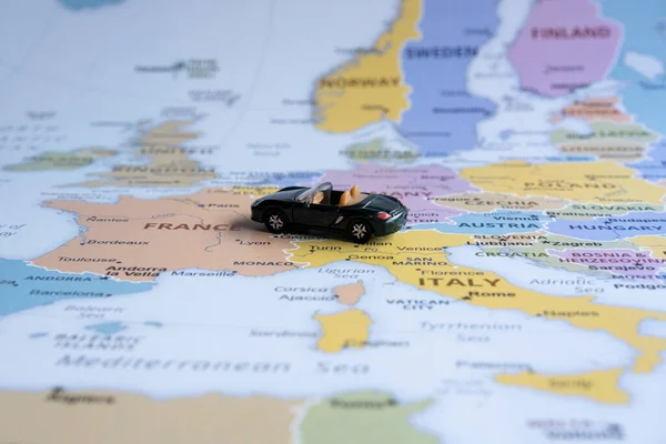 Toy car travels on Europe map, sitting view, vacation and destination concept, miniature green sport car going to France from  Italy , worldwide tour, Europe map idea