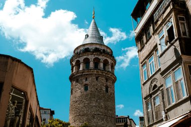 İstanbul 'daki iki bina arasındaki Galata Kulesi, Türkiye' deki eski ünlü bina, tarihi mimarisi ve mavi gökyüzü, turizm ve gezi fikri, İstanbul 'daki seyahat beldesi
