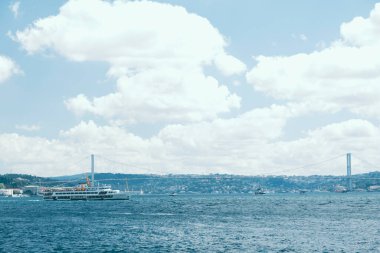 İstanbul, Galataport 'tan İstanbul' a uzanan Boğaz Köprüsü manzarası, mavi bulutlu gökyüzü, boğazda feribotla gökyüzü, İstanbul 'dan güzel manzara, arabalarla büyük köprü, gemiyle şehir manzarası