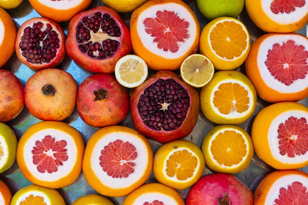 Colorful cut fruits, background with organic fresh citrus, healthy life and vegetarian idea, colored juicy fruits, cut pomegranate orange grapefruit lemon in market stand, food wallpaper and backdrop