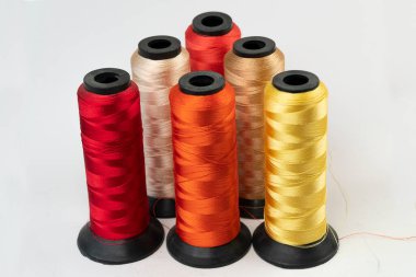 Beyaz arkaplanda izole edilmiş renkli bobbin ipleri, üst görünümde seçici odak iplikleri