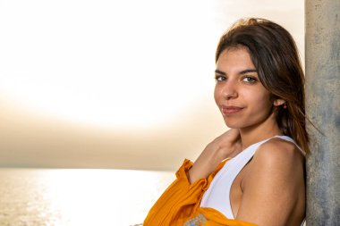 Çekici bir esmer kadının yoğun bir bakışla kameraya baktığı altın deniz batımı. Soldaki boşluğu kopyala. Yaz sonu konsepti