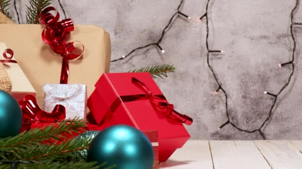 クリスマスのコンセプト クリスマスの贈り物がたくさん入ったジュート袋 白い板の上に赤いリボンで赤 銀のパッケージ 背景のクリスマスの装飾や輝くライト — ストック動画