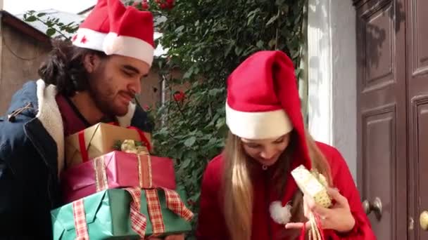 Junger Mann Mit Nikolausmütze Bringt Seiner Freundin Geschenke Sie Lächelt — Stockvideo