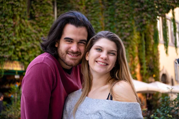 Roma 'ya seyahat eden güzel bir çift. Genç çift tarihi merkezde bir sokakta selfie çekiyor. Arka planda sarmaşıkla kaplı bir bina.