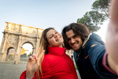 Peynir deyin! Genç ve çekici bir çift Roma 'nın tarihi merkezinde Titus Kemeri' nin yanında selfie çekiyor..