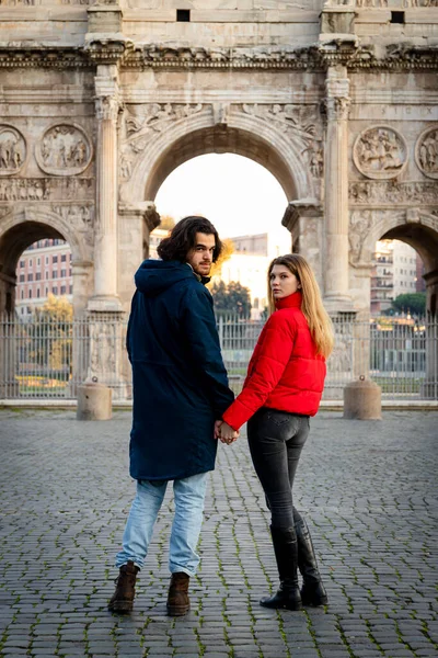 一对年轻夫妇要去罗马这对年轻夫妇手牵手 在泰特斯拱门前散步 — 图库照片