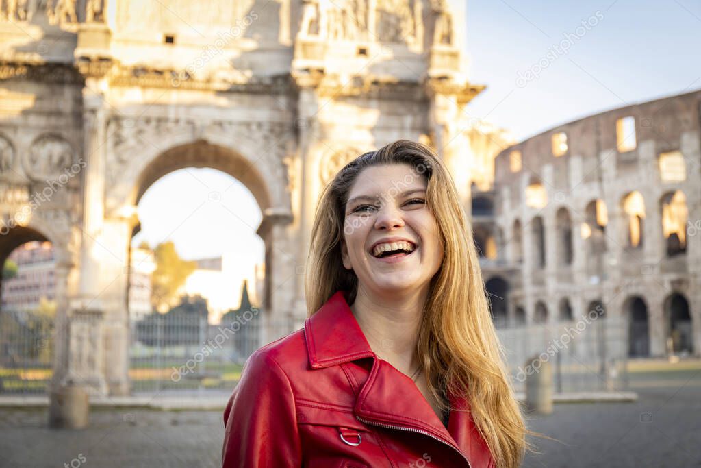 Young blond woman traveling to Rome. Beautiful woman smiling and posing fot a photo in front of the Arch of Titus.