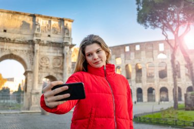 Kışın Colosseum 'un önünde selfie çeken genç ve çekici bir kadın. Sevgi dolu anılar.