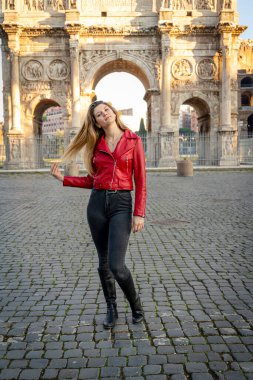 Roma 'ya seyahat eden genç bir kadın. Güzel sarışın kadın Titus 'un kemerinin önünde kendi fotoğrafını çekiyor..