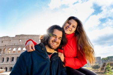 Roma 'ya seyahat eden genç bir çift. Çift gülümsüyor ve Colosseum 'un önünde selfie çekiyor..