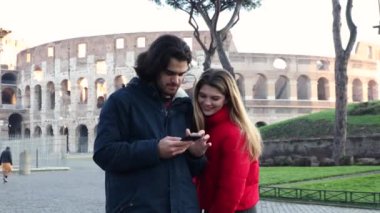 Roma 'ya seyahat eden genç bir çift. Mutlu genç çift akıllı telefondan Colosseum 'un önünde bir mesaj izliyor..