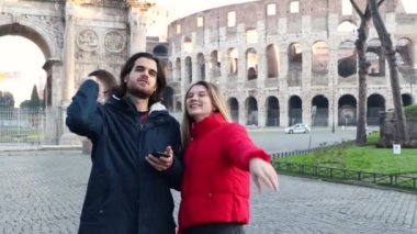 Roma 'ya seyahat eden genç bir çift. Mutlu çift Colosseum 'un önünde duruyor ve o da erkek arkadaşını işaret ediyor..