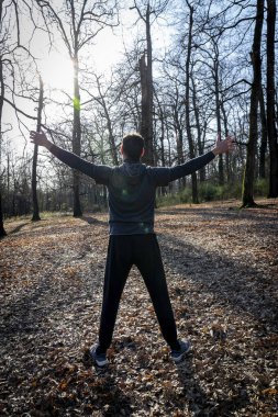 Koşucu ormanda geriniyor. Arkadan kollarını açmış bir adam görüldü..